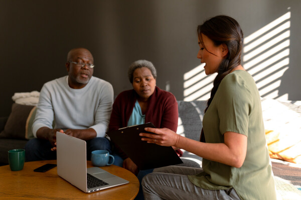 african american senior couple having meeting with asian female financial advisor home